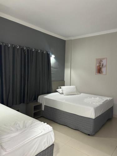 a bedroom with two beds and a black curtain at D` Garcia Hotel in Três Lagoas