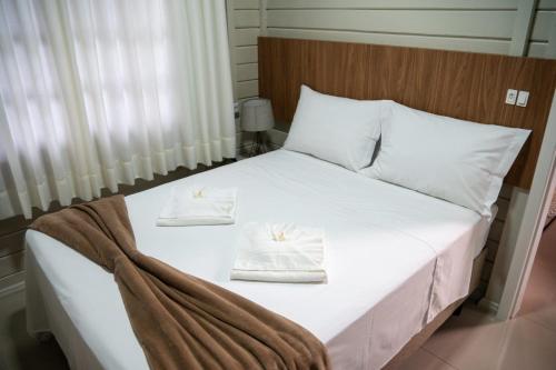 a bed with two white towels on top of it at Sítio Monte Frederico in Nova Trento