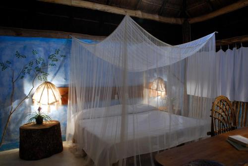 a bedroom with a canopy bed with white curtains at Hotel Puerta Calakmul in Conhuas