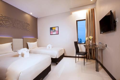a hotel room with two beds and a television at Verse Lite Hotel Gajah Mada in Jakarta