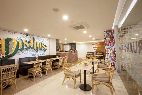 a restaurant with tables, chairs, and a television at Verse Lite Hotel Gajah Mada in Jakarta