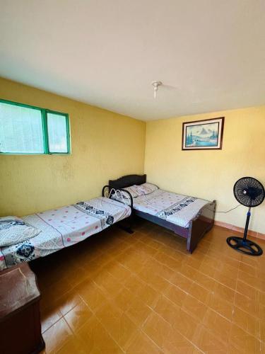 a room with two beds and a fan in it at Casa quinta en Girardot in Girardot