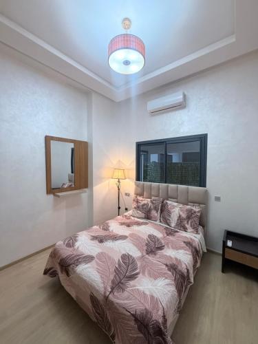 a bedroom with a bed and a lamp and a mirror at Ocean park , for married couples and families only ,للعائلات و المتزوجين فقط Luxury fully furnished one bedroom flat next to zenata beach with five avialable swimming pool at the compound in Casablanca