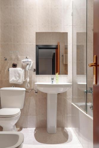 a bathroom with a white toilet and a sink at Santacruz in Oviedo