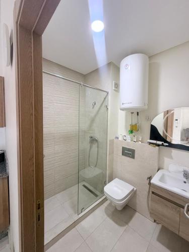 a bathroom with a shower and a toilet and a sink at Ocean park , for married couples and families only ,للعائلات و المتزوجين فقط Luxury fully furnished one bedroom flat next to zenata beach with five avialable swimming pool at the compound in Casablanca