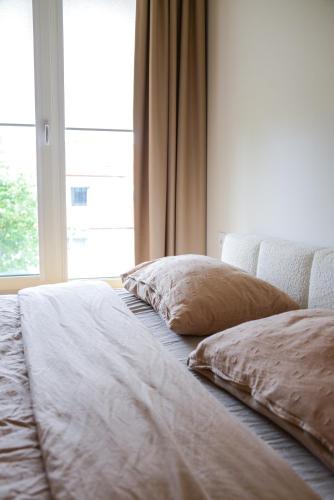 a bed with two pillows sitting next to a window at Erdvūs apartamentai Prie Jūros in Melnragė