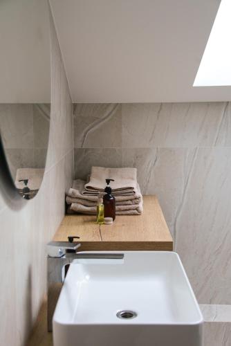 a bathroom with a white sink and towels on a counter at Erdvūs apartamentai Prie Jūros in Melnragė