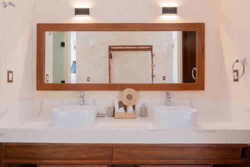a bathroom with two sinks and a large mirror at Nalhá Hotel Boutique y Villas Bacalar in Bacalar