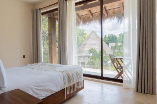 a bedroom with a bed and a large window at Nalhá Hotel Boutique y Villas Bacalar in Bacalar