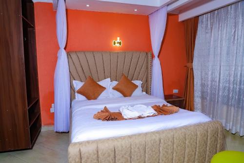 a bedroom with a large bed with orange walls at Lee Njiru Resort in Nakuru