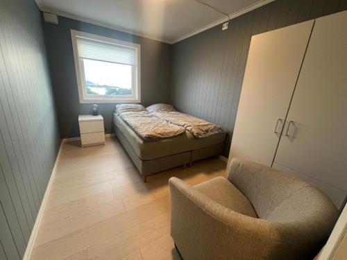 a bedroom with a bed and a chair and a window at Basement apartment on Ulstein in Ulstein