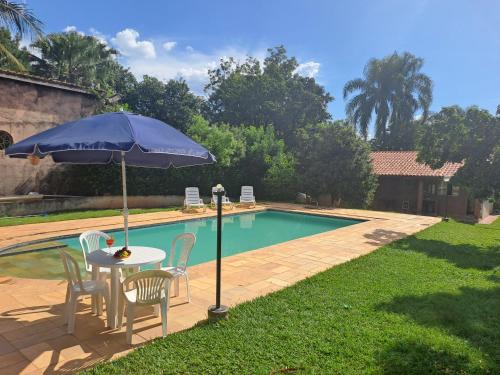 a table and chairs with an umbrella next to a pool at Chácara Vivenda Aconchego in Itupeva