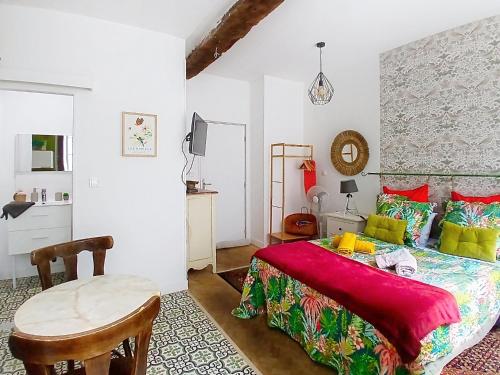 a bedroom with a bed and a table and a kitchen at Les Glycines Oloron in Oloron-Sainte-Marie
