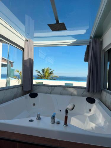 a white bath tub with a view of the ocean at Pousada Pinocchio in Maricá