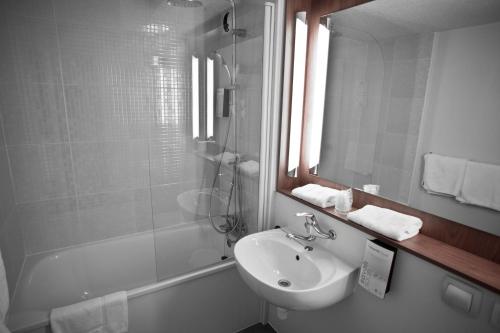 a bathroom with a sink and a mirror and a shower at Ampaline HOTEL - Perigueux Boulazac in Boulazac