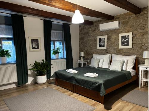 a bedroom with a bed and a stone wall at Vitamin K73 Vendégház in Boldogkőváralja