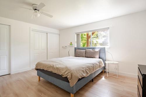 a white bedroom with a bed and a window at Serene Garden Suite in Delta