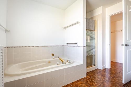 a white tub in a bathroom with a shower at Serene Garden Suite in Delta