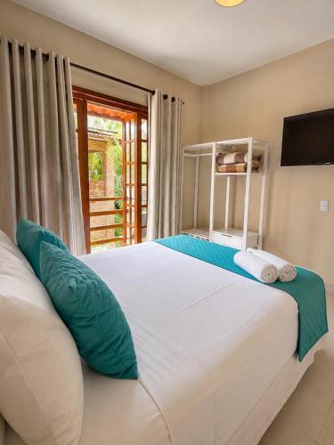 a bedroom with a large white bed with a window at Pousada Villa Bougainville Maragogi in Maragogi
