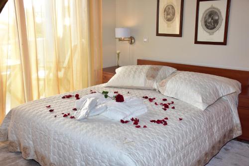 Una cama con rosas y una manta blanca. en Blue Diamand, en Mégara