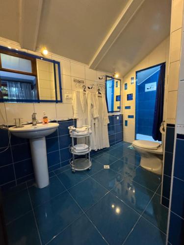 a blue tiled bathroom with a sink and a toilet at Georgios Ranch in Tsodoreti