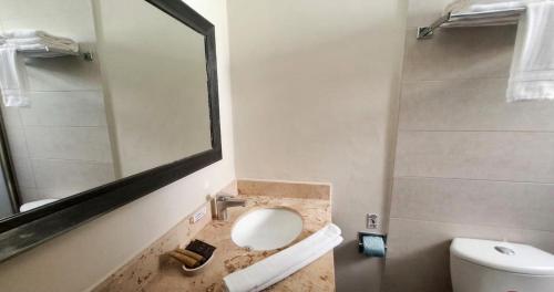 ein Badezimmer mit Waschbecken, Spiegel und Toilette in der Unterkunft Sina Suites Cancun - Adults Only in Cancún