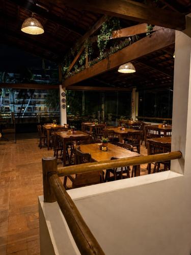 a restaurant with wooden tables and chairs and lights at Pousada Villa Bougainville Maragogi in Maragogi