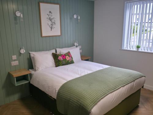a bedroom with a bed with white sheets and pink flowers at Garden House Rooms in Kirkwall