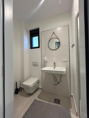 a white bathroom with a sink and a toilet at L 32 Sea view in Lepetani