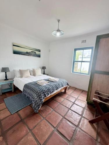 a bedroom with a bed and a table and a window at Coast Cottages Langebaan in Langebaan