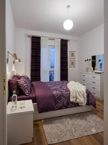 a bedroom with a purple bed and a window at Spacious Central Apartment with Panoramic Views in Tirane