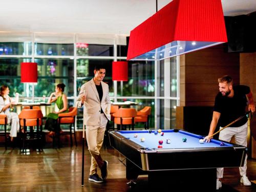 two men playing a game of pool in a restaurant at Pullman Doha West Bay in Doha