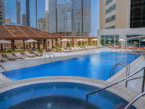 a large swimming pool with chairs and a building at Pullman Doha West Bay in Doha