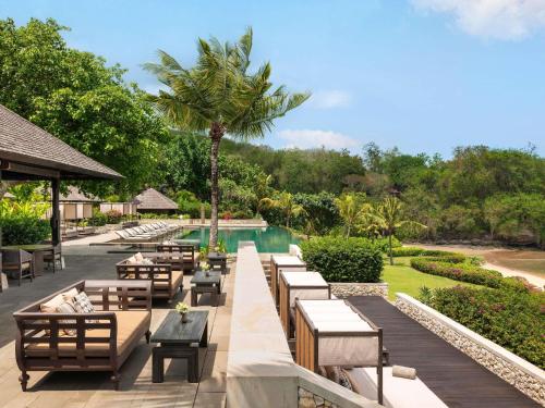 a resort with a pool and tables and chairs at Raffles Bali in Jimbaran