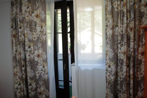 a room with curtains and a window with a door at Raiul Sânzienelor in Sărata-Monteoru