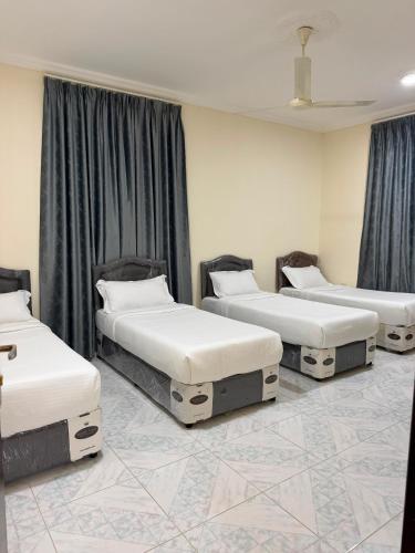 drei Betten in einem Zimmer mit schwarzen Vorhängen in der Unterkunft أجاويد لشقق المفروشة 1 Ajaweed Residence in Salalah