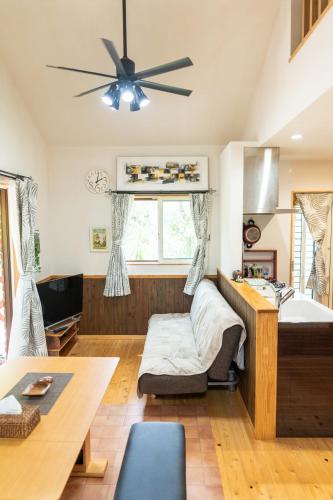 a living room with a ceiling fan and a bed at 今帰仁森風テラス in Nakijin