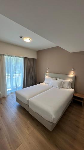 a large white bed in a room with a window at Hotel João Paulo II in Braga