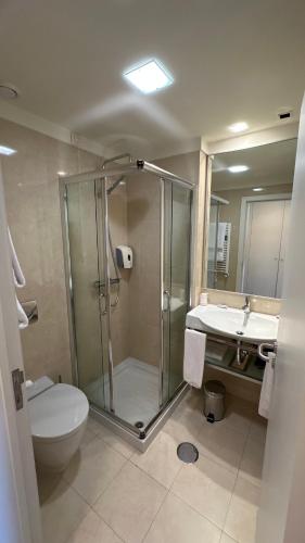 a bathroom with a shower and a toilet and a sink at Hotel João Paulo II in Braga