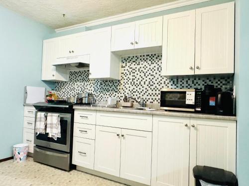 a white kitchen with white cabinets and a microwave at Zoe house in Victoria