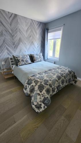 a bedroom with a bed with a comforter and a window at Bienvenue Chez Mymy! in Sept-Îles