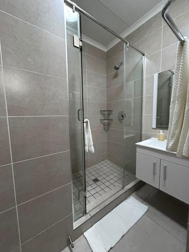 a bathroom with a glass shower with a sink at Studio Luxe The Aura Your Calm Escape in Northriding