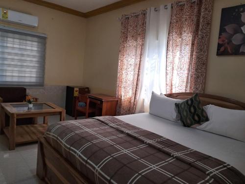 a bedroom with a bed and a window and a table at Immanuel Victory Hotel & Restaurant in Ajenkotoku