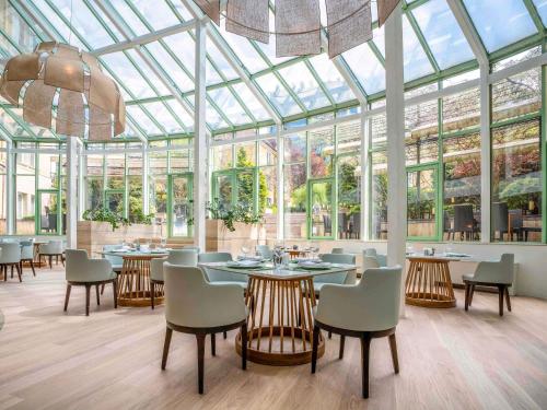 ein Restaurant mit Wintergarten, ausgestattet mit Tischen und Stühlen in der Unterkunft Maison Sofia - MGallery in Sofia