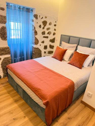 a bedroom with a bed with orange and white pillows at Refúgio d’Aldeia da Serra in Seia