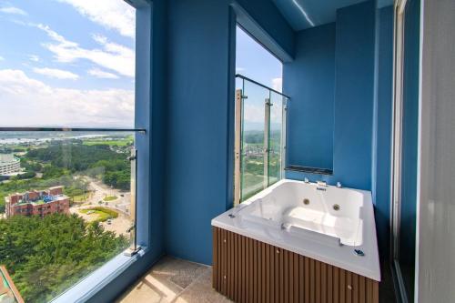 a blue bathroom with a tub and a large window at 플럼바고올스위트1809 in Sangun-ni