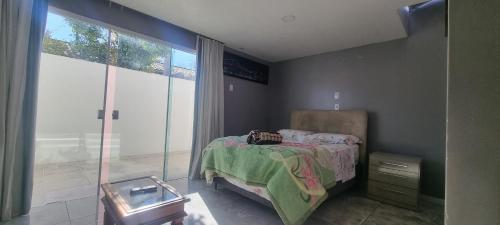 a bedroom with a bed and a large window at Cantinho das Orquídeas! in Pelotas