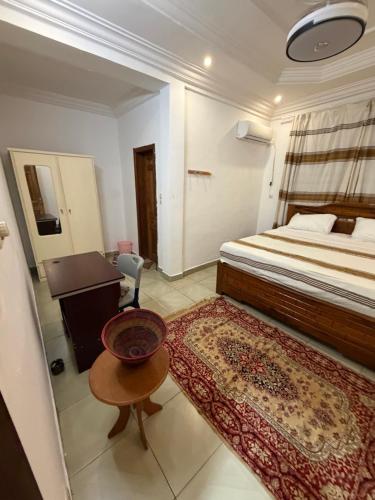 a bedroom with a bed and a table and a desk at Abbe Residence in Bamako