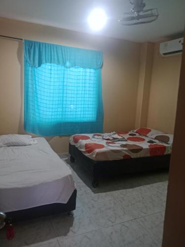 two beds in a room with a blue window at Apartamento centro oriente in Coveñas