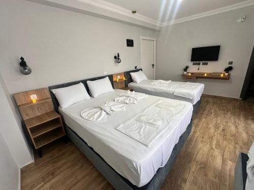 a bedroom with two beds with white sheets and a television at Avka Palace in Edirne